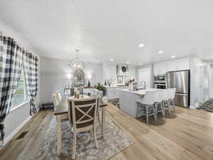Dining area featuring recessed lighting, a textured ceiling, light wood-style flooring, and a chandelier