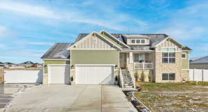 Craftsman-style house featuring stone siding, board and batten siding, and driveway