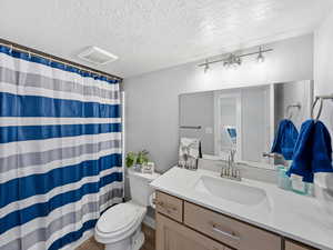 Bathroom with a shower with curtain, vanity, and a textured ceiling