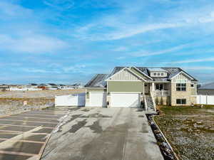 Craftsman inspired home with board and batten siding, driveway, a residential view, a garage, and solar panels