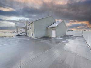 Property exterior at dusk with a fenced backyard, a gate, large oversize concrete rv pad and stucco siding
