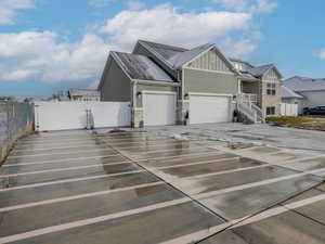 View of home's exterior with board and batten siding, a gate, stone siding, driveway, and an attached garage