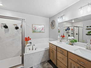 Full Master bathroom featuring a marble finish shower, a bath, double vanity, and a textured ceiling
