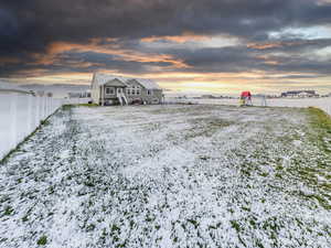 Half Acre Yard covered in snow with a fenced backyard and a playground