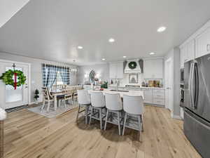Kitchen featuring appliances with stainless steel finishes, a breakfast bar area, a textured ceiling, an island with sink, and decorative light fixtures