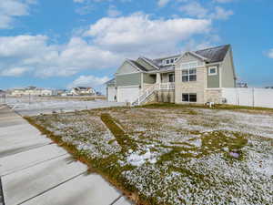 Snow covered house featuring stone siding, board and batten siding, driveway, an attached garage, and roof with shingles