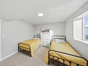 Bedroom with a textured ceiling and light carpet