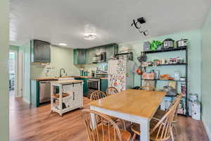 Kitchen with green cabinets, stainless steel appliances, light wood-style flooring, and butcher block countertops