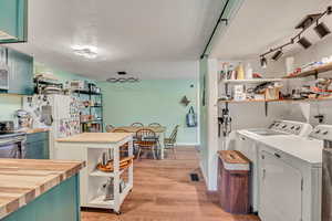 Laundry room featuring light wood-type flooring, washing machine and dryer, and track lighting