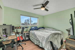 Bedroom featuring an office area, wood finished floors, and a ceiling fan