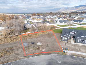 Aerial perspective of suburban area with property parcel outlined and a mountainous background