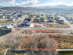 Aerial view of residential area with property parcel outlined and a mountainous background