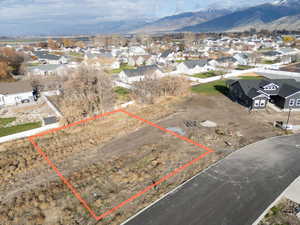 Aerial perspective of suburban area with property parcel outlined and a mountain backdrop