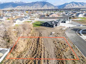 Aerial perspective of suburban area with a mountain backdrop and property parcel outlined