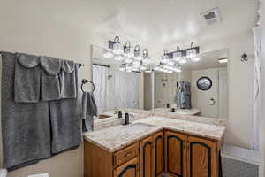 Full bath featuring a textured ceiling, vanity, and a shower with shower curtain