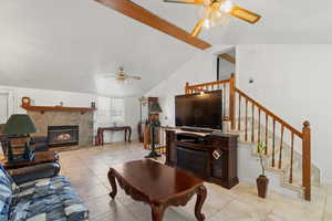 Living area with a stone fireplace, a ceiling fan, and light tile patterned flooring