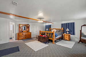 Carpeted bedroom featuring ceiling fan and a textured ceiling