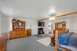 Carpeted bedroom with a textured ceiling, ceiling fan, and a wood stove