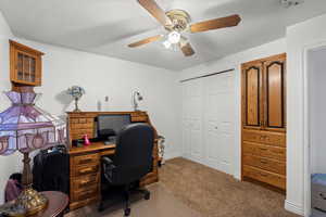 Carpeted office featuring a textured ceiling and a ceiling fan