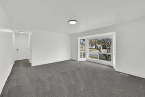 Unfurnished room with dark colored carpet and baseboards