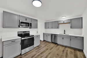 Kitchen with gray cabinets, stainless steel appliances, and light wood-type flooring