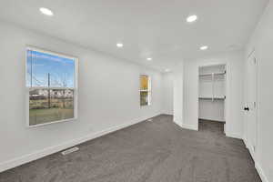 Unfurnished bedroom with a walk in closet, carpet flooring, and recessed lighting