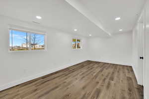 Below grade area with light wood-style flooring and recessed lighting