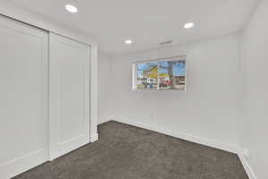Unfurnished bedroom with a closet, dark colored carpet, and recessed lighting
