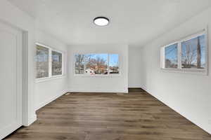 Unfurnished room featuring dark wood-style flooring, plenty of natural light, and a textured ceiling