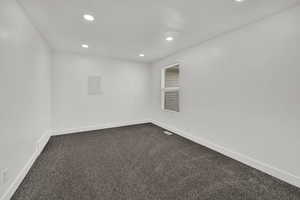 Unfurnished room featuring dark carpet, recessed lighting, and electric panel