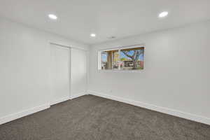 Unfurnished bedroom featuring dark carpet, recessed lighting, and a closet