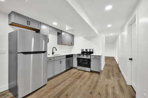 Kitchen with gray cabinetry, appliances with stainless steel finishes, recessed lighting, and light wood-style flooring