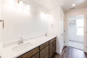Photo of home built in past by OLO. Bathroom featuring double vanity, a walk in closet, dark wood-style flooring, and recessed lighting