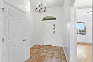Foyer featuring inlaid floor details, a chandelier, light tile patterned flooring, a high ceiling, and plenty of natural light