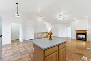 Kitchen featuring hanging light fixtures, a center island, lofted ceiling, a multi sided fireplace, and open floor plan
