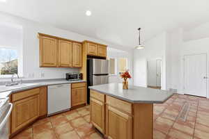 Kitchen with stainless steel refrigerator, dishwasher and range, light tile patterned floors, hanging light fixtures, a kitchen island, and lofted ceiling