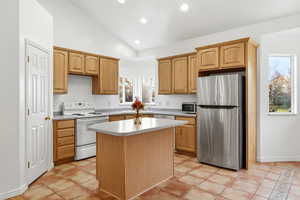 Kitchen with vaulted ceiling, freestanding refrigerator, white electric range, light countertops, and a kitchen island