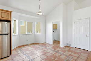 Unfurnished dining area with light tile patterned flooring and high vaulted ceiling