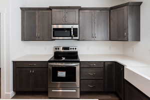 Photo of home built in past by OLO. Kitchen featuring appliances with stainless steel finishes, dark brown cabinets, and dark wood-style floors