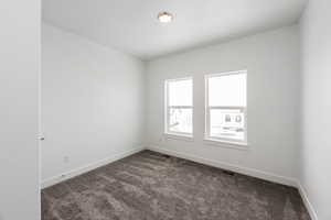 Unfurnished room with dark colored carpet and baseboards
