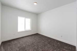 Empty room with baseboards and dark colored carpet