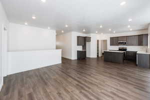 Photo of home built in past by OLO. Kitchen with dark brown cabinetry, light countertops, open floor plan, stainless steel appliances, and a center island