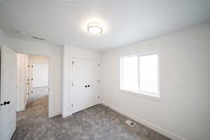 Unfurnished bedroom with dark colored carpet and a closet