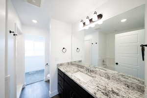 Bathroom with a bath, vanity, recessed lighting, and dark wood-style floors