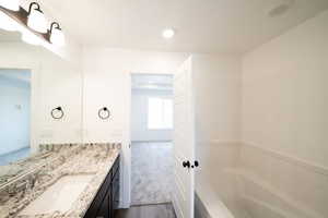 Full bath with vanity, a garden tub, dark carpet, and recessed lighting
