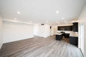 Photo of home built in past by OLO.  Kitchen featuring open floor plan, a kitchen island, stainless steel appliances, recessed lighting, and light wood-style floors