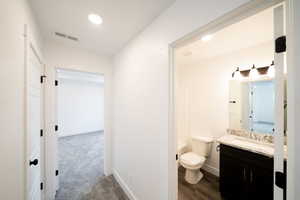 Bathroom featuring vanity, recessed lighting, and dark colored carpet
