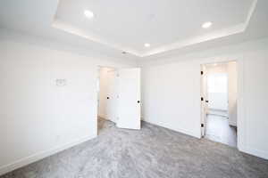 Photo of home built in past by OLO.  Unfurnished bedroom with recessed lighting, carpet, a tray ceiling, and connected bathroom