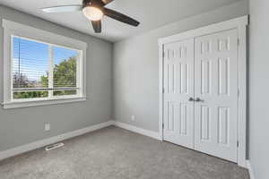 Unfurnished bedroom featuring light colored carpet, ceiling fan, and a closet