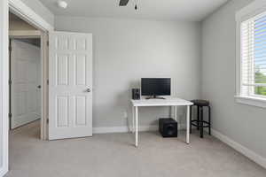 Home office with light carpet and a ceiling fan
